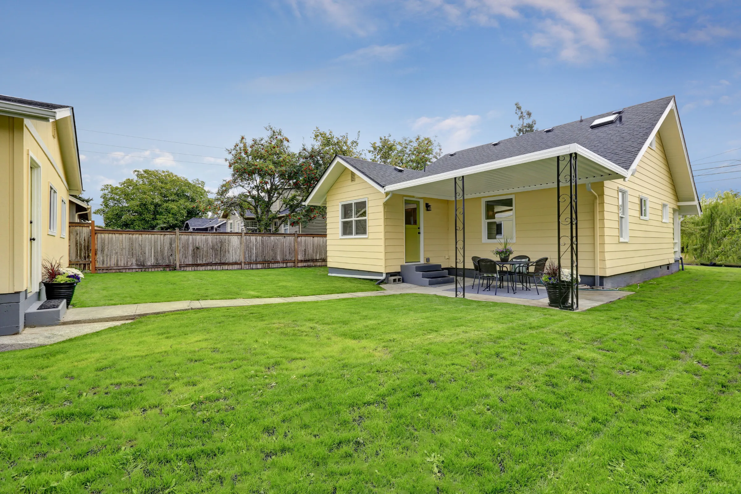 Modern backyard ADU detached accessory dwelling unit located behind a contemporary house with green lawn and swimming pool